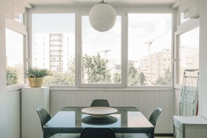 Ein Essbereich mit Tisch und Stühlen, großen Fenstern und einer Pendelleuchte.