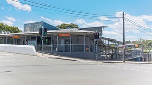 A pedestrian crossing with traffic lights, a sign for 'Padstow', and a modern building with a flat roof. - Self-contained studio near train station (Padstow)