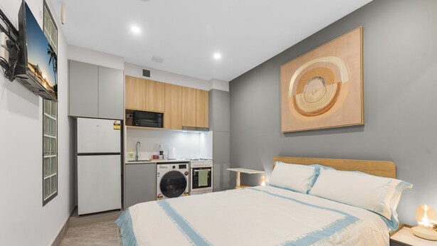 A bedroom with a bed, bedside table, and a wall-mounted artwork. - Self-contained studio near train station (Padstow)