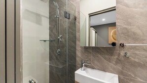 A modern bathroom with a glass-enclosed shower, a white bathtub, and a large mirror above the sink. - Self-contained studio near train station (Padstow)