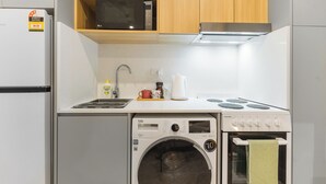 A compact kitchen with a microwave, stove, sink, and washing machine. - Self-contained studio near train station (Padstow)