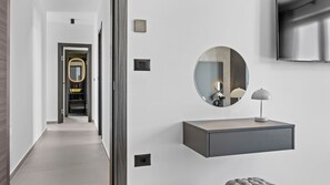 En hall med en modern sminkbord, en rund spegel och en väggmonterad TV.