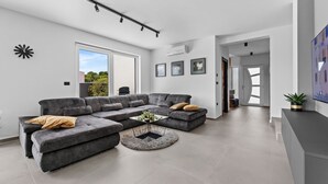 Ein modernes Wohnzimmer mit einem Ecksofa, einem Couchtisch und einem großen Fenster.