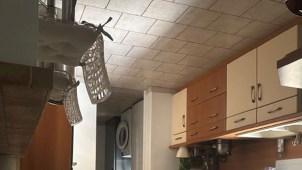 Una cocina moderna con armarios de madera, horno empotrado e iluminación colgante.