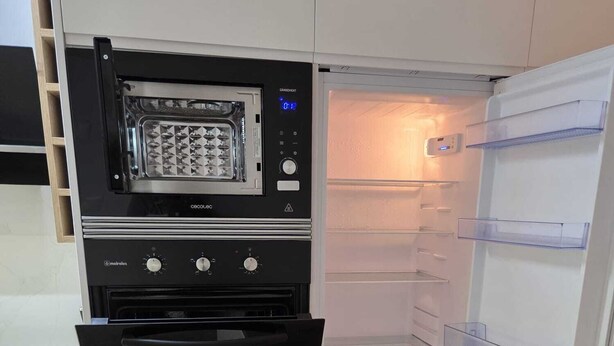 Una cucina compatta con forno integrato, microonde e lavatrice.