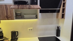 Una cucina compatta con un piano di lavoro nero, mobili in legno, un piano cottura integrato e una cappa aspirante nera.