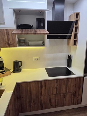 A compact kitchen with a black countertop, wooden cabinets, a built-in stove, and a black range hood. - MELISSA'S HOUSE
 2-bedroom house in pleasant Seixal with AC (Seixal)