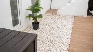 Una zona esterna moderna con una panchina in legno, una pianta in vaso e una scala che conduce a un livello superiore.