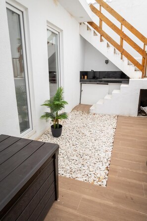 A modern outdoor area with a wooden bench, a potted plant, and a staircase leading to an upper level. - MELISSA'S HOUSE
 2-bedroom house in pleasant Seixal with AC (Seixal)