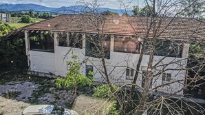 En byggnad med ett tak täckt av tegelpannor, en veranda och utsikt över bergen.