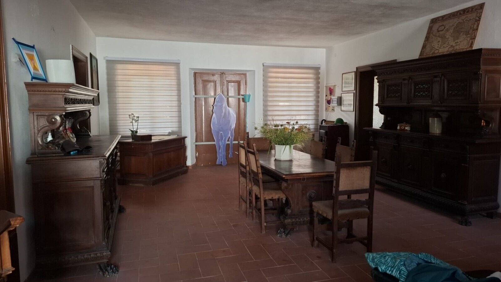 Ein Essbereich mit Holztisch und Stühlen, einem Schrank und einem Fenster mit Jalousien.