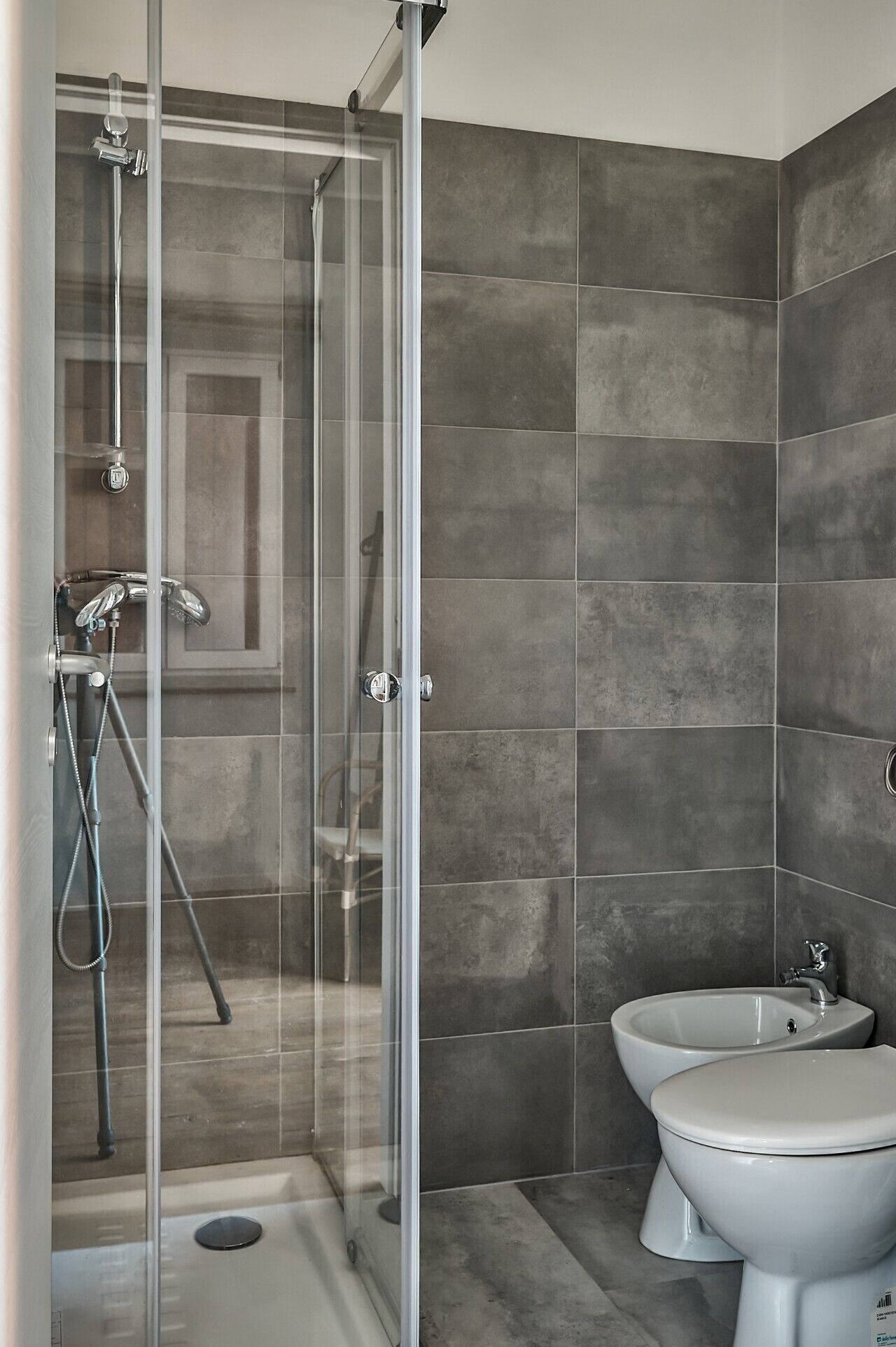 Ein modernes Badezimmer mit einer gläsernen Duschkabine, einem Bidet und einer Toilette.