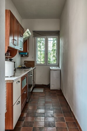 Una cocina compacta con estufa a gas, horno empotrado y refrigerador pequeño.