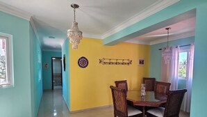 Uma área de jantar com uma mesa e cadeiras, um candelabro e uma parede com detalhes decorativos.