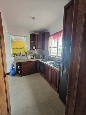 Eine Küche mit Holzschränken, einem Gasherd, einer Mikrowelle und einem Kühlschrank.