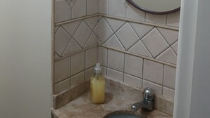 Un bagno con lavandino, specchio e dispenser di sapone.