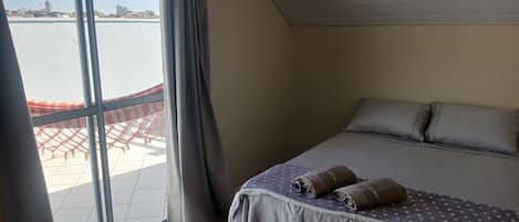 Un dormitorio con cama, cortinas y vista al agua.