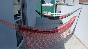 Un'amaca legata tra due pareti su un balcone con pavimento piastrellato.