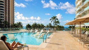 A poolside area with lounge chairs and a pool, surrounded by palm trees and a clear sky. - Ilikai Hotel | 1-Bedroom Ocean View Suite | Car Incl. w/ 6 nights | ILK-937 by KBM (Honolulu)