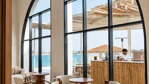 Un interior moderno con amplios ventanales arqueados, un bar junto a la piscina y zonas de estar.