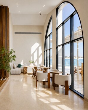 Una habitación amplia con ventanas grandes, un sofá, sillas y una mesa.