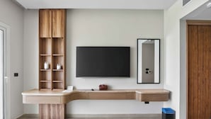Un baño moderno con tocador integrado, un espejo grande y un televisor de pantalla plana montado en la pared.