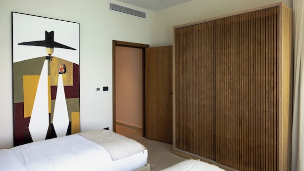 Una habitación de hotel con una cama, un armario y un cuadro en la pared.