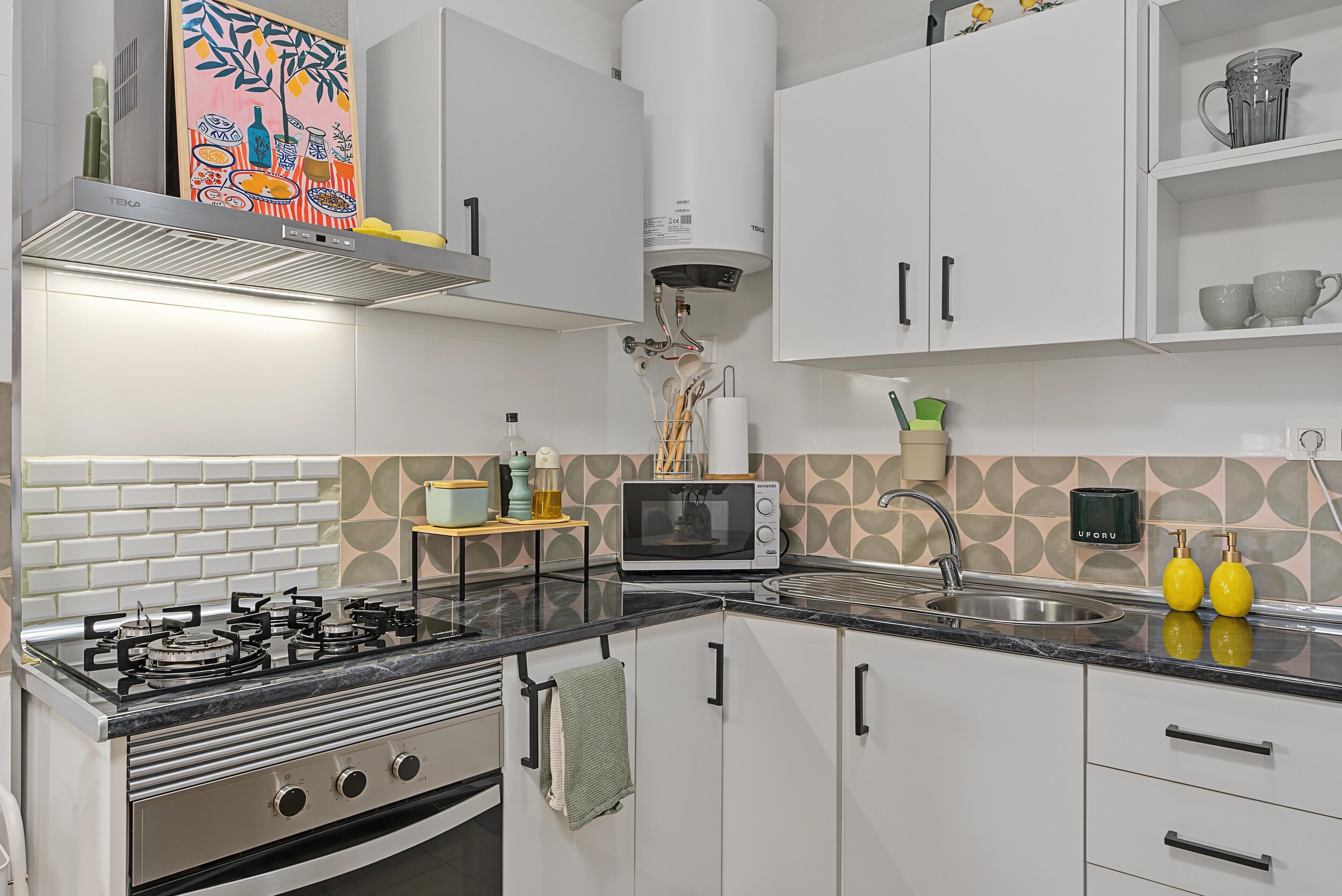 Une cuisine moderne avec des meubles blancs, une cuisinière à gaz, un four à micro-ondes et un évier.
