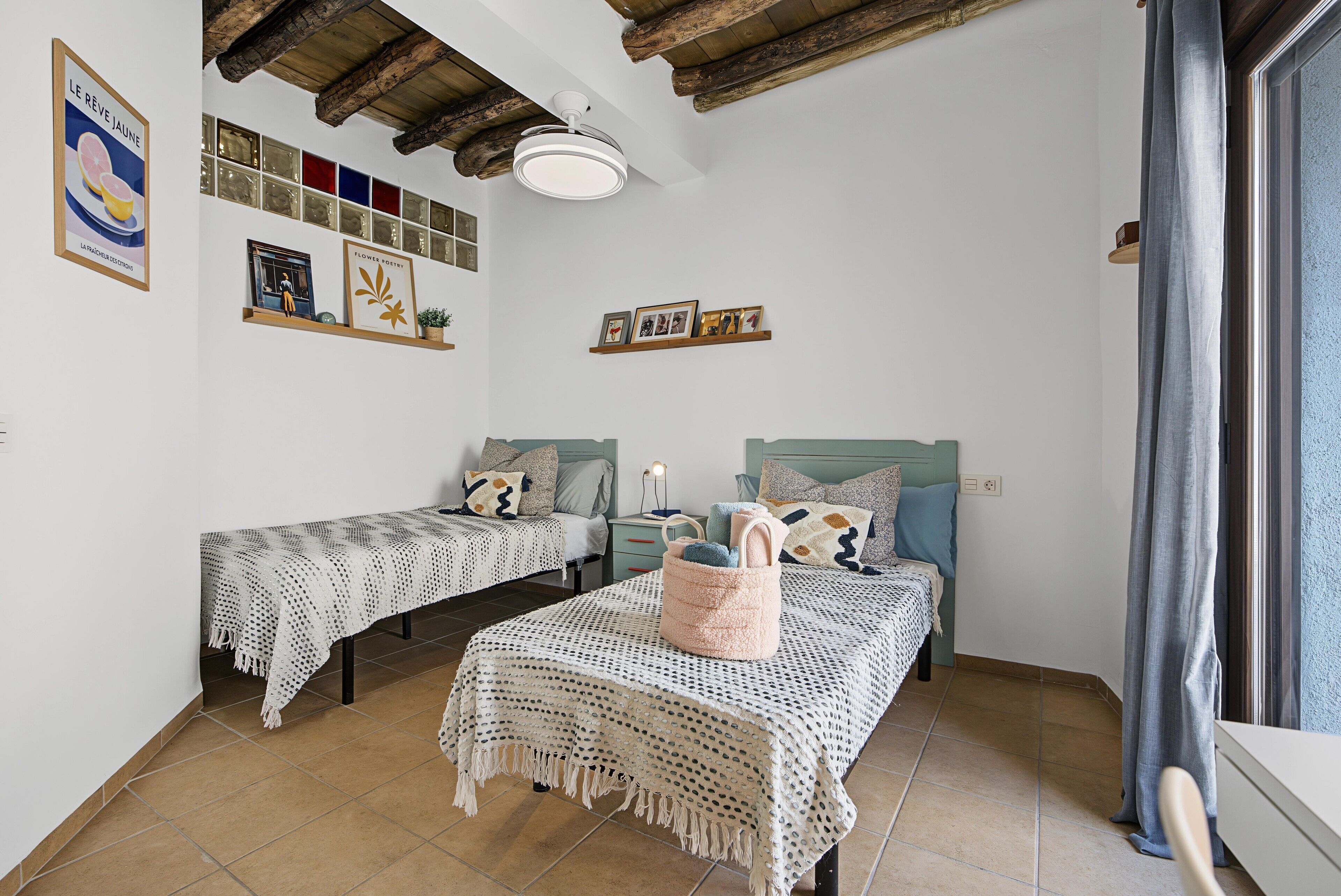 Ein Zimmer mit zwei Betten, einem Deckenventilator und einer Wand mit gerahmten Bildern und einem Schild.