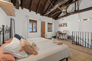 A bedroom with a large bed, a desk, and a staircase. - Casa Rubia Limón Holiday Home (Béznar)