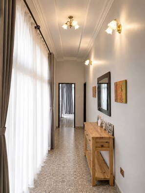 Un couloir avec un banc en bois, un miroir et des luminaires fixés au mur.