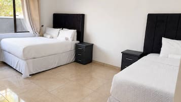 A hotel room with two beds, a nightstand, and a window with curtains.