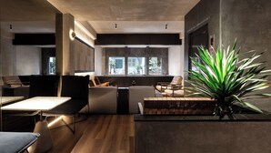 Un interior moderno con una zona de estar, una planta y vistas a través de grandes ventanales.