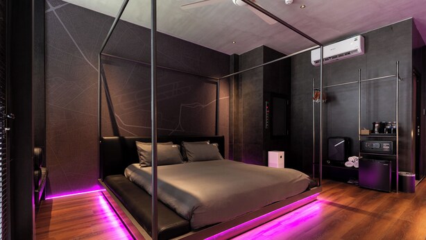 Un dormitorio moderno con una cama, un armario, un espejo y un equipo de aire acondicionado instalado en el techo.