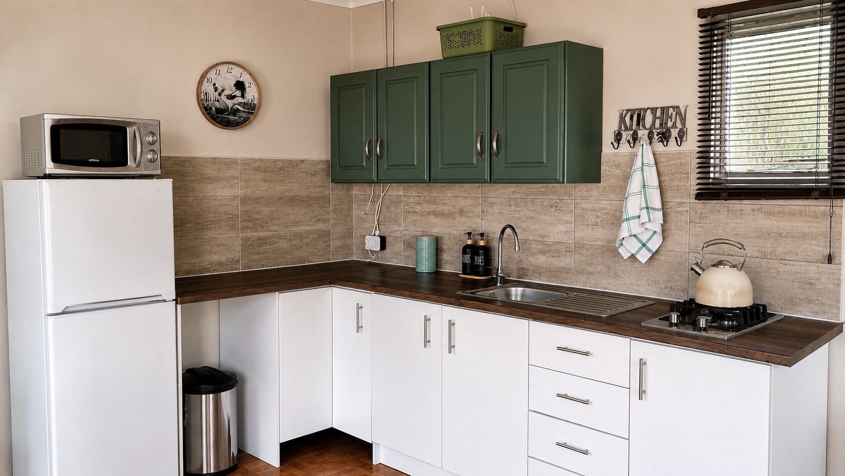 Una cocina con microondas, lavamanos, armarios y hervidor.