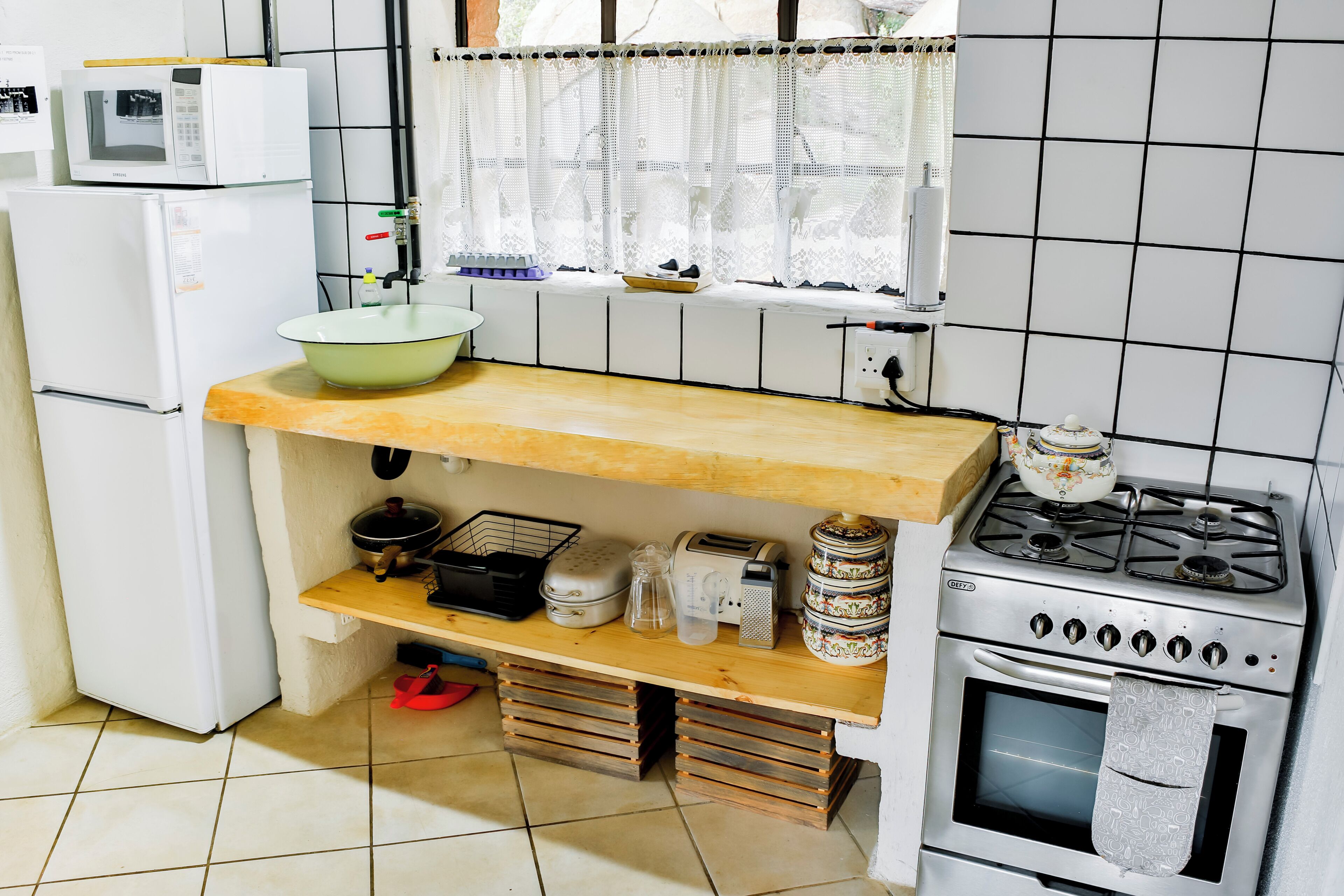 Una cocina compacta con microondas, estufa y varios electrodomésticos sobre estantes de madera.