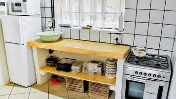Una cocina compacta con microondas, estufa y varios electrodomésticos sobre estantes de madera.