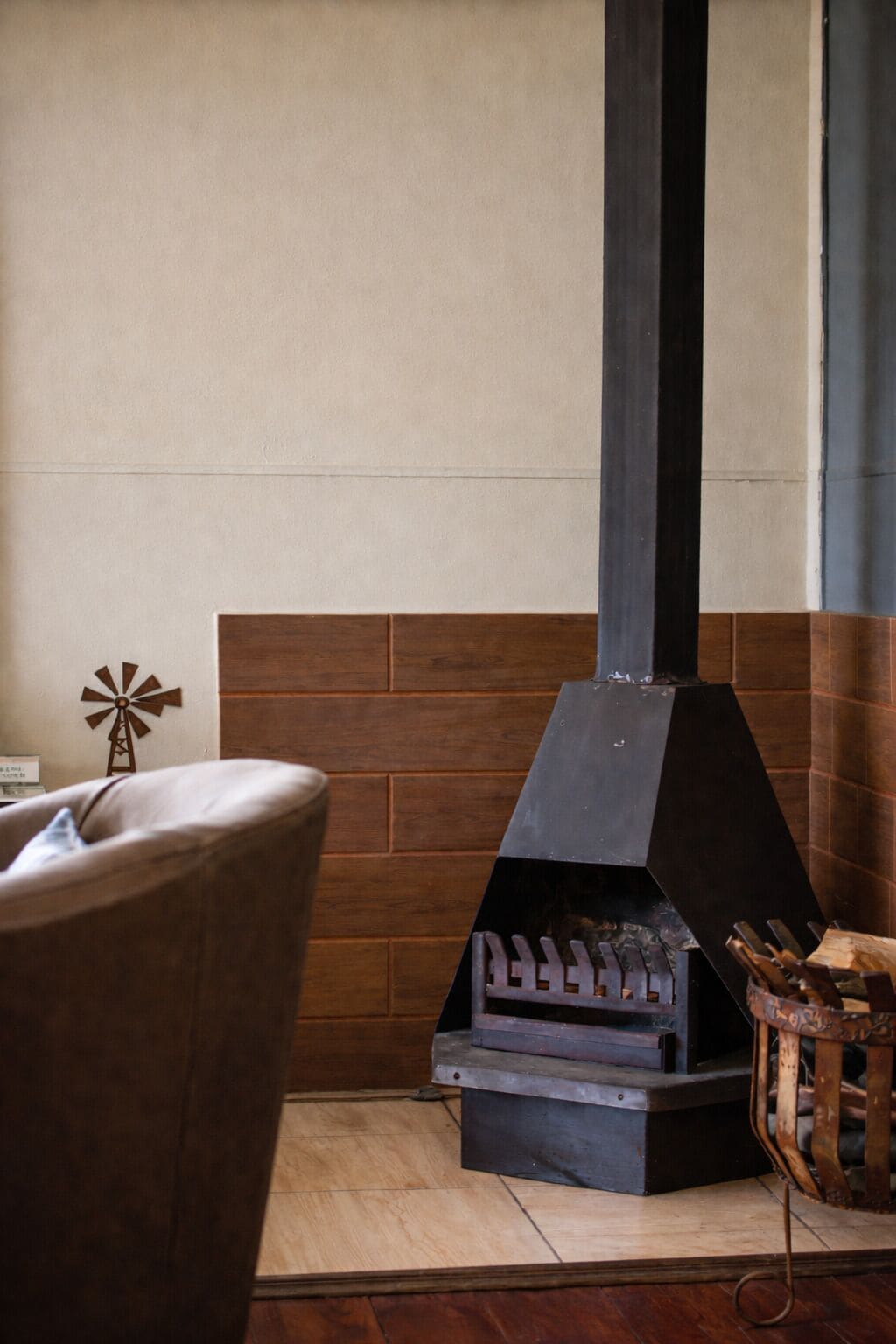 A fireplace with a metal chimney, a brick wall, and a wooden floor.