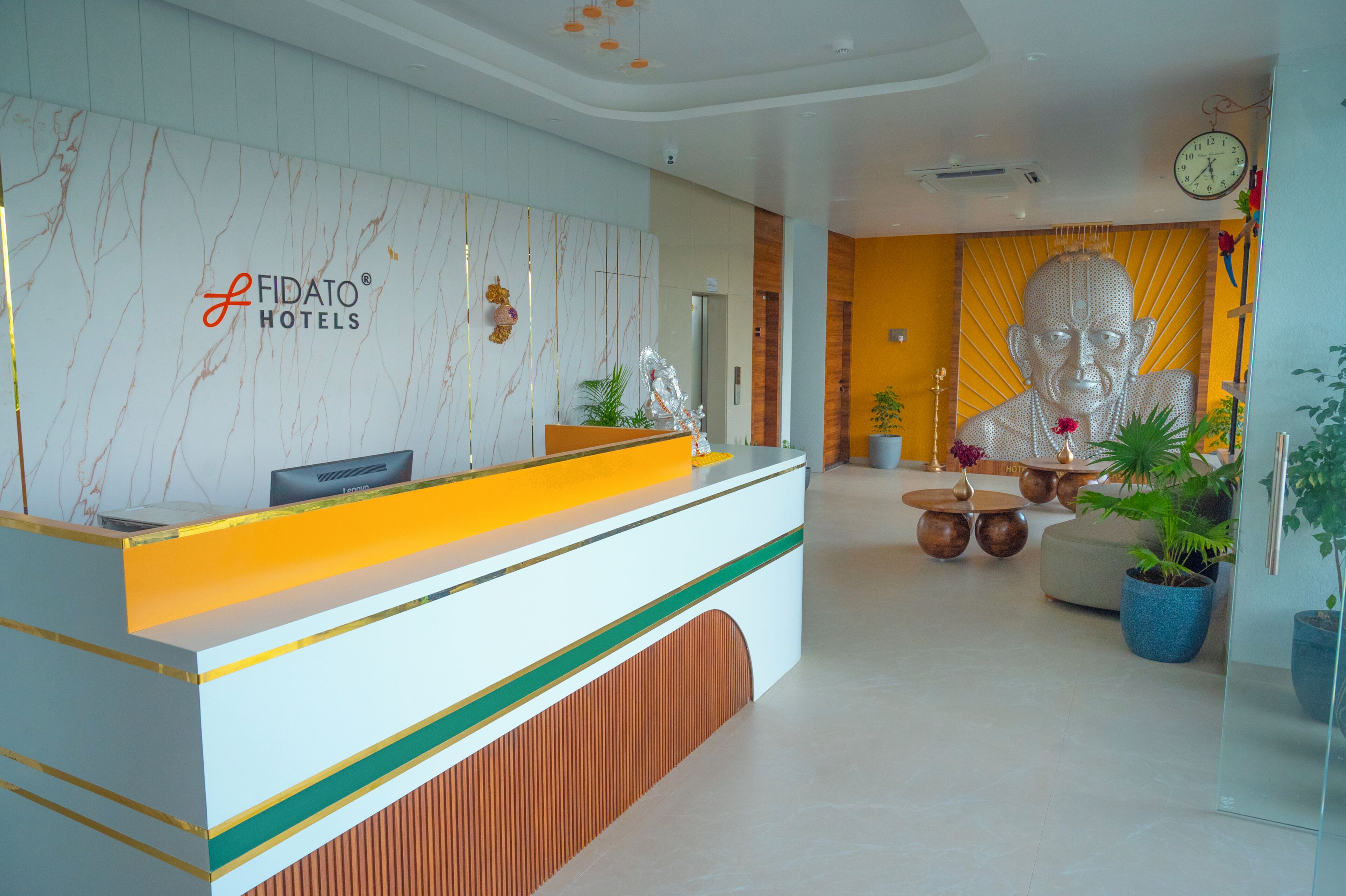 A reception desk with a modern design, a large Buddha statue, and a clock on the wall.