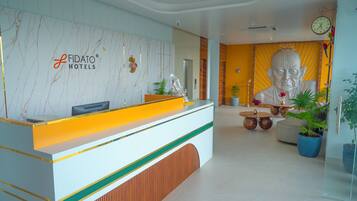 A reception desk with a modern design, a large Buddha statue, and a clock on the wall.