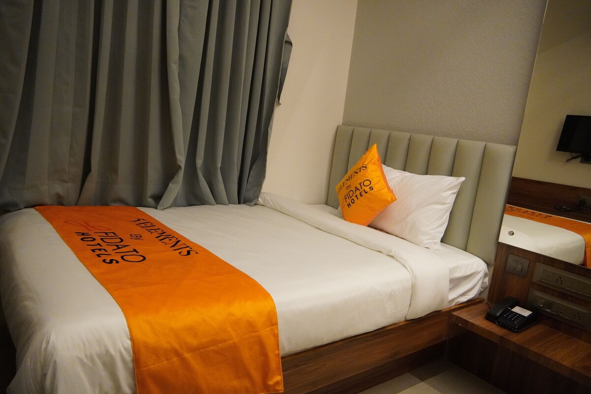 Una habitación de hotel con una cama, una mesita de noche, un teléfono y un televisor montado en la pared.