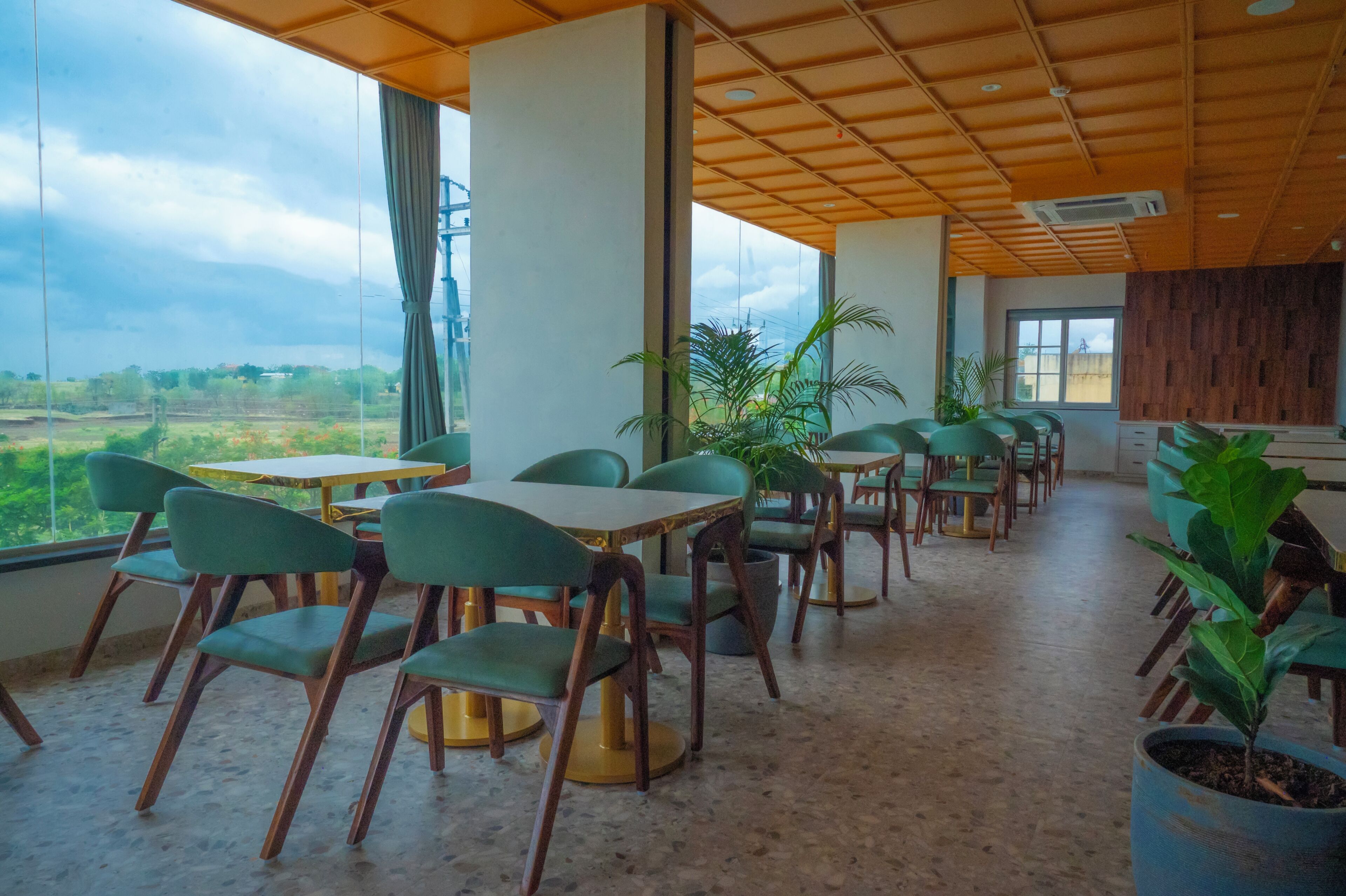 A spacious dining area with high ceilings and large windows, offering views of the outdoors.