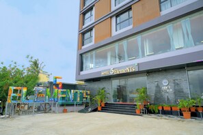 Un hotel con fachada moderna, amplias ventanas y un cartel que dice 'Hotel 5 Elements'.