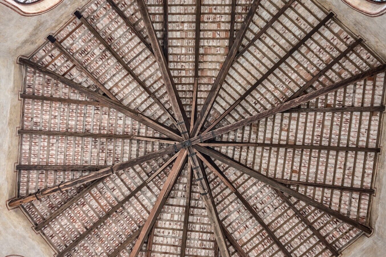 Un plafond circulaire orné d’un motif radial de poutres en bois et d’une texture évoquant la brique.