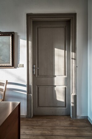 A closed door with a handle, a small metal plate, and a wooden floor.