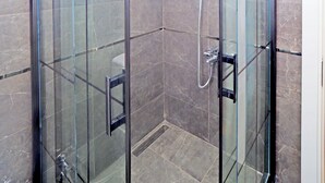 A glass-enclosed shower with a handheld showerhead and a wall-mounted faucet. - ARGES SUİTE HOTEL (istanbul)
