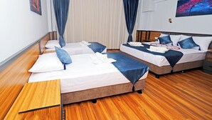 A hotel room with two beds, wooden flooring, a ceiling fan, and a painting on the wall. - ARGES SUİTE HOTEL (istanbul)