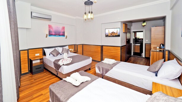 A hotel room with two beds, a desk, a mirror, and artwork on the walls. - ARGES SUİTE HOTEL (istanbul)