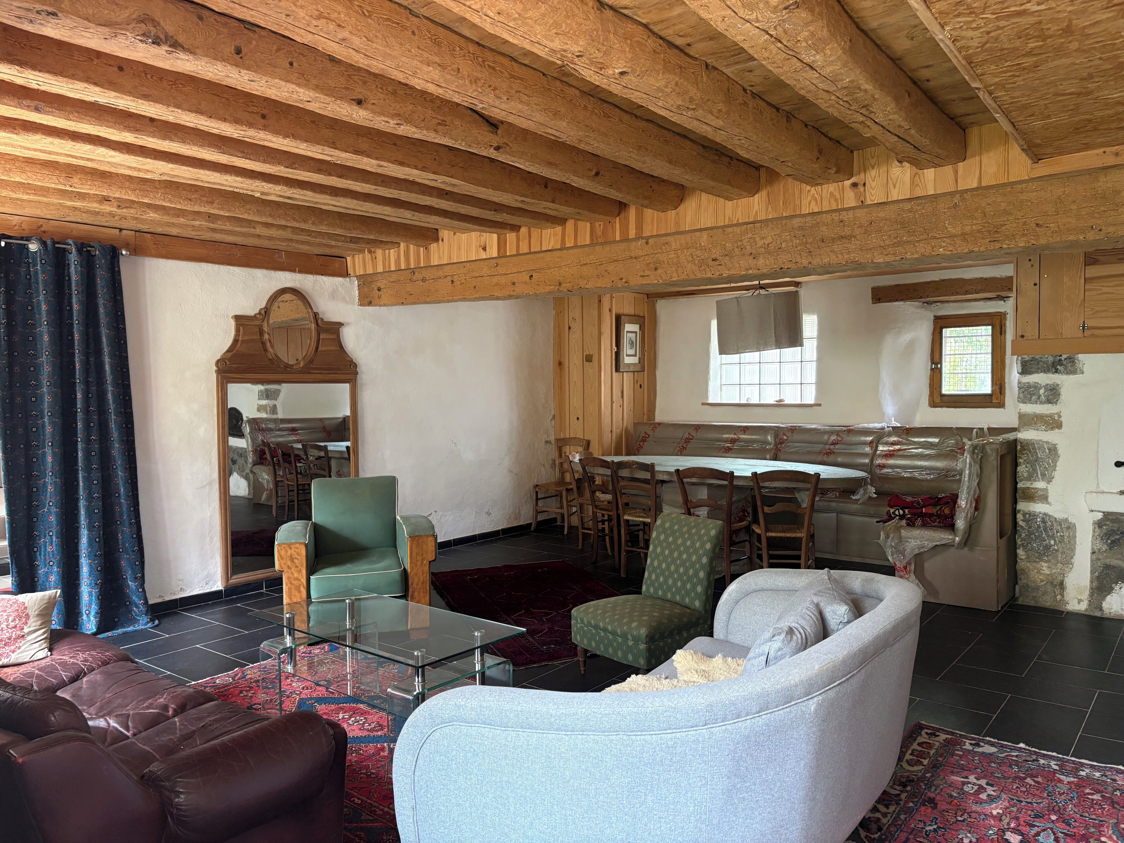Una habitación con paneles de madera, una mesa de centro de vidrio, sofás de cuero y un comedor con sillas y una mesa.