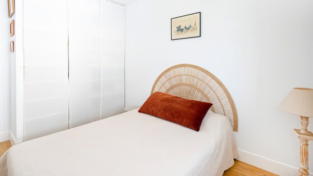 Ein Schlafzimmer mit einem Bett, einem Kleiderschrank, einem Bild an der Wand und einer Lampe.